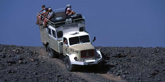 Afrika, West-Sahara, Algerien: Die Reisenden genießen während der Fahrt die Aussicht vom Dach des LKWs.